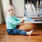 Little,Child,Helping,To,Unload,Dishwasher.,Baby,Girl,Sitting,On