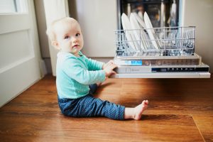 Little,Child,Helping,To,Unload,Dishwasher.,Baby,Girl,Sitting,On